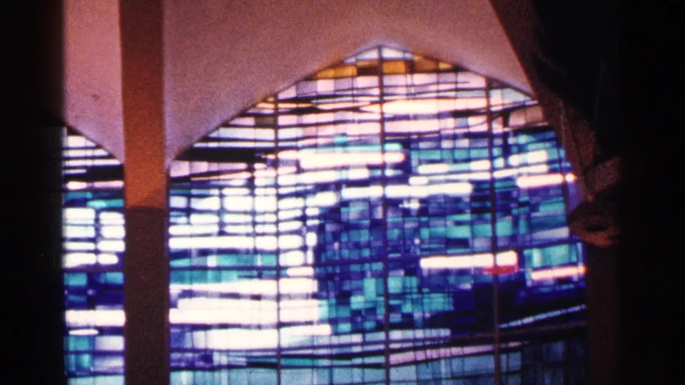 1964 New York City home-movie view of a luminous geometric stained glass window with blue and white panes.