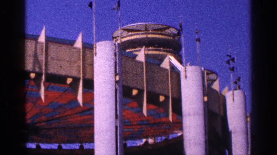 1964 New York City 8mm exterior showing a large modern building with white concrete columns, flags, and red-blue facade panels.