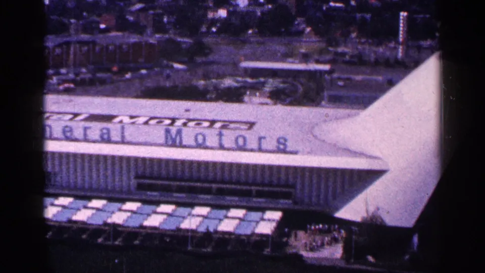 1964 New York World's Fair view of the General Motors pavilion, showing the large white canopy form, partial roof lettering, facade, and grounds.
