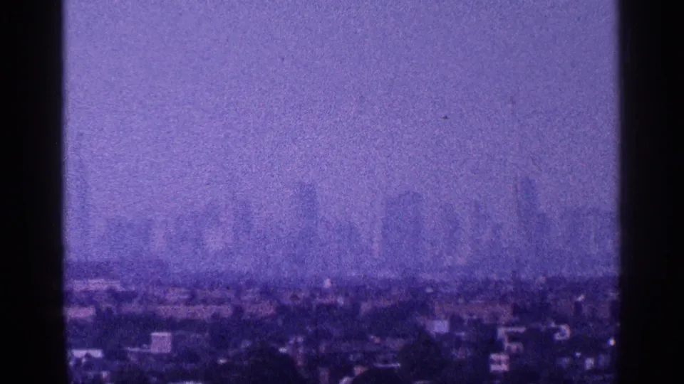 New York City skyline silhouettes sit behind a low urban foreground in purple-tinted 1964 8mm home-movie footage.