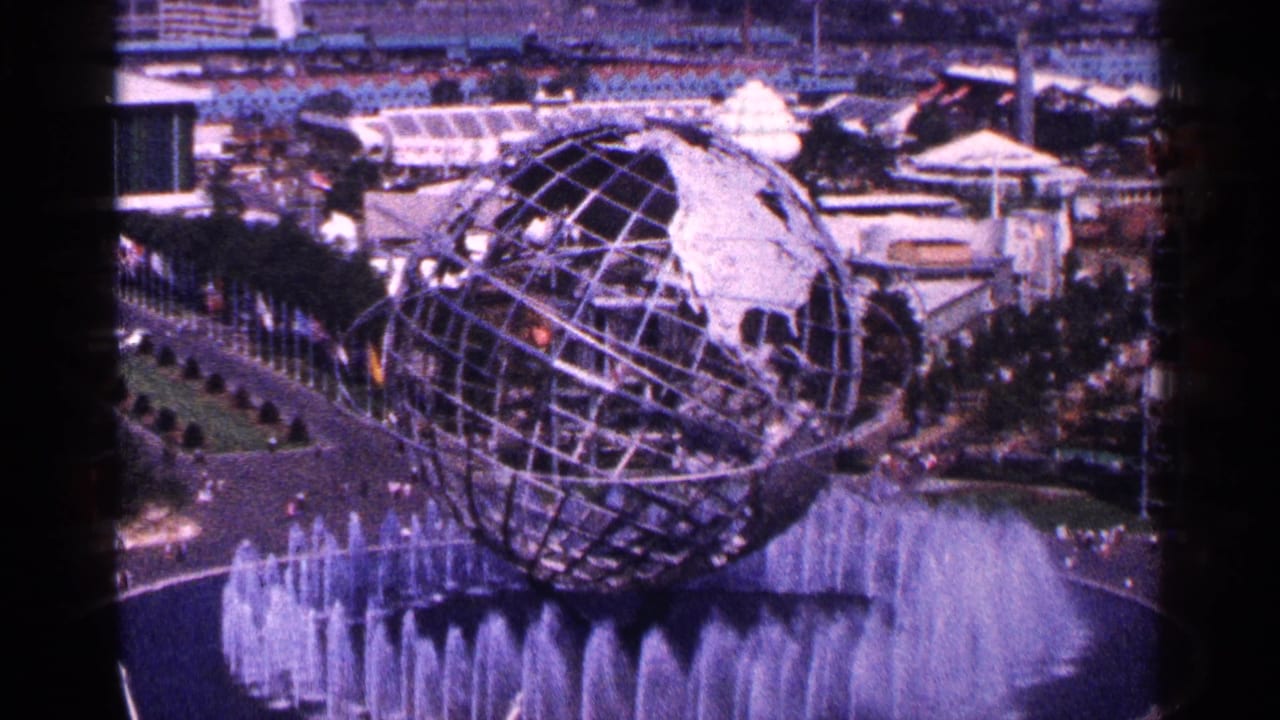 Unisphere above a circular fountain with visitors and fairground structures around it.