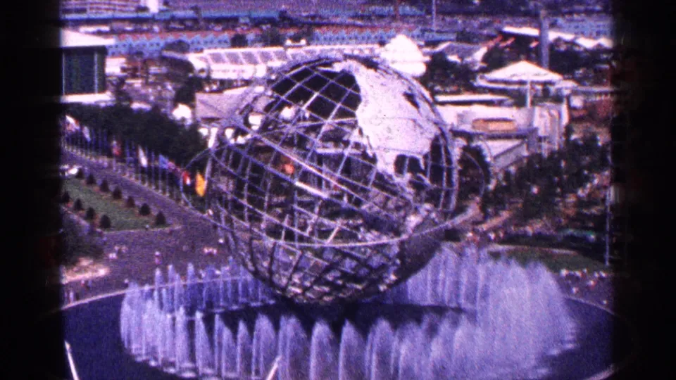Aerial-style 8mm view of the Unisphere at the 1964 New York World's Fair, with fountain spray and visitors along the paths.