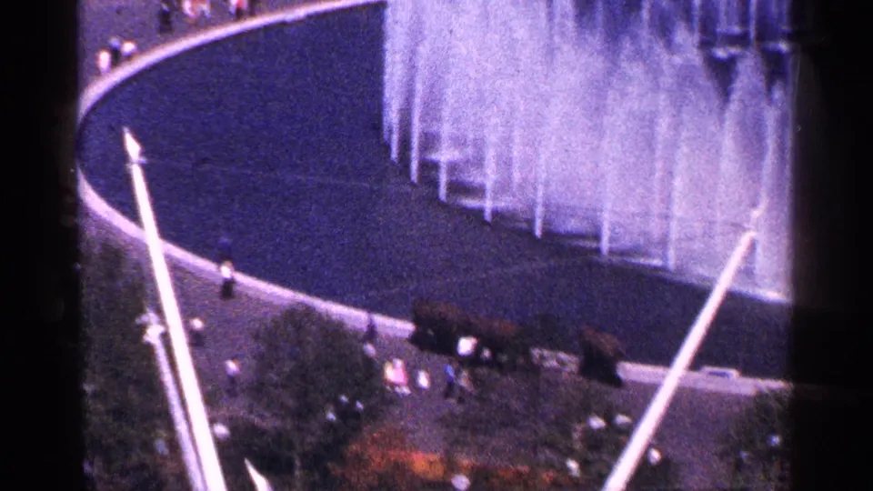 Closer 8mm view of the Unisphere fountain basin at the 1964 New York World's Fair, emphasizing water jets, pool edge, and nearby visitors.