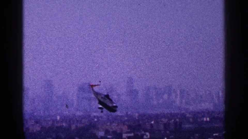1964 New York City frame showing a small helicopter silhouetted over rooftops with the skyline faint in the haze.