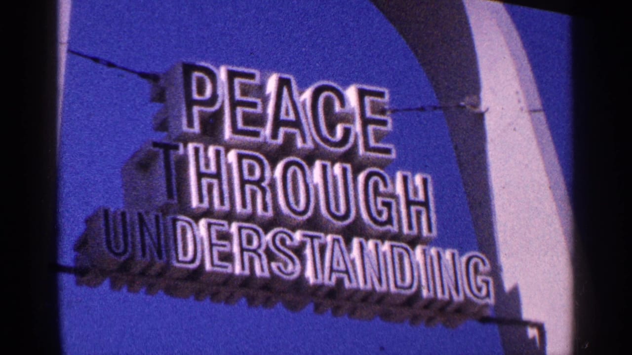 1964 New York City 8mm frame showing a Peace Through Understanding sign beside a curved fairground-style structure under blue sky.