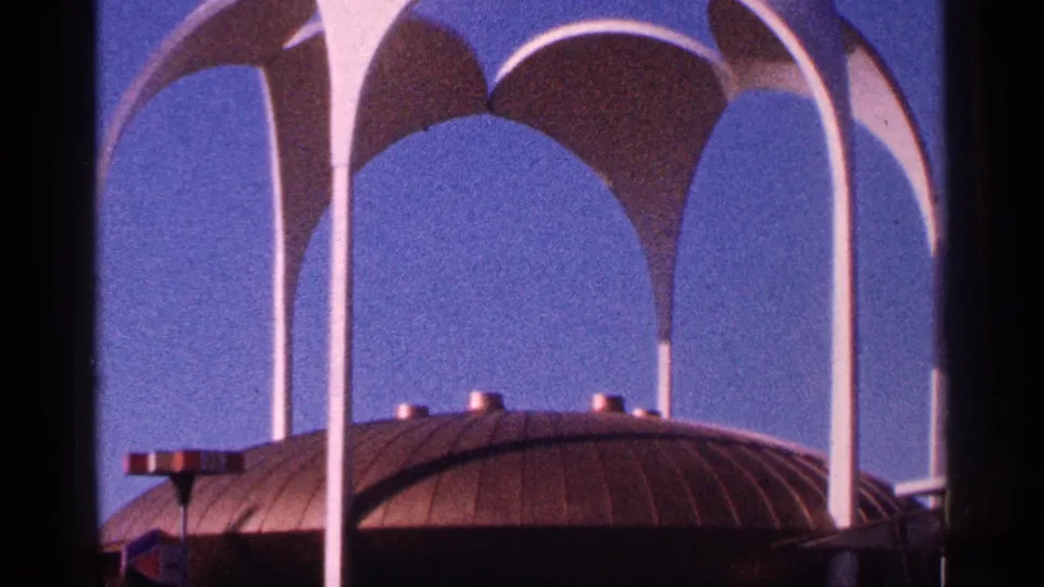 1964 New York City 8mm view of white arches and a domed roofline, with film border and saturated sky visible.