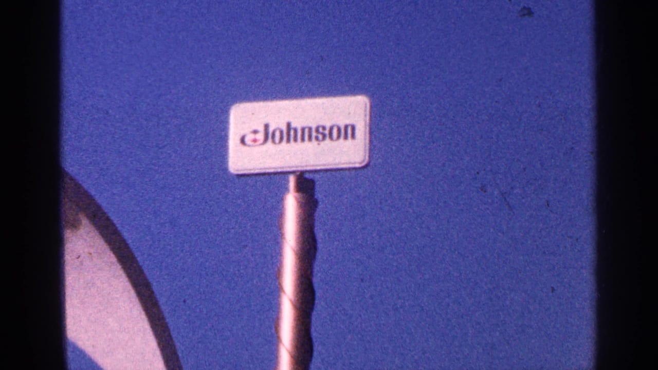 Johnson sign on a pole beside a dark frame edge and blue sky.