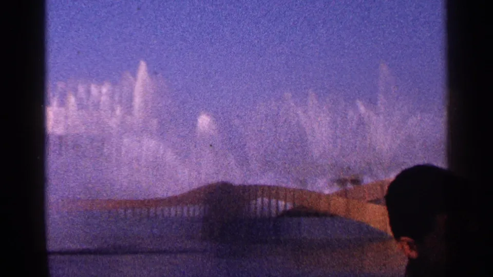 1964 New York City frame with fountain jets in the background and a silhouetted spectator at the right edge.