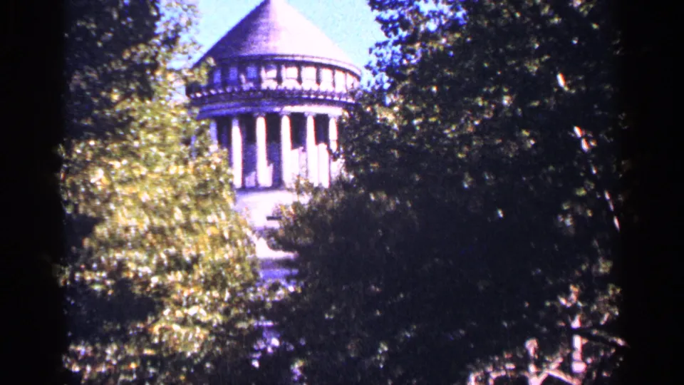 1964 New York City home-movie view of a domed classical structure seen through trees, with strong shadow and bright sky.