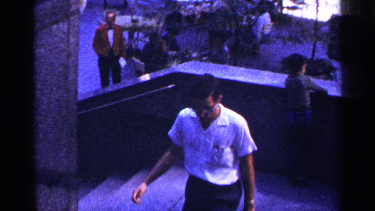 Man in a white shirt walks up concrete stairs with pedestrians behind him.