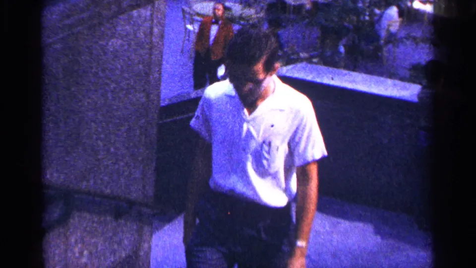 The man continues up the stairway in New York City, framed close to a concrete wall with street activity behind him.