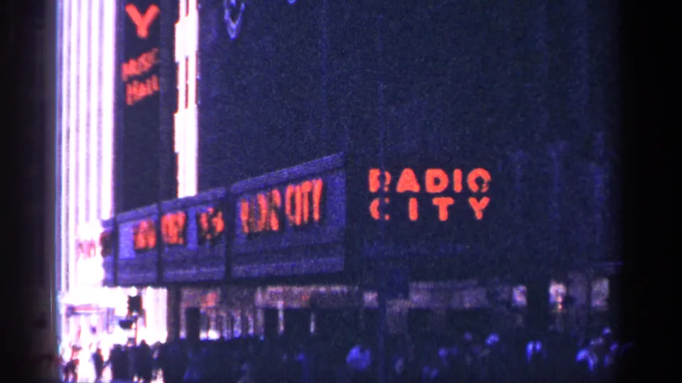 A second view of the Radio City Music Hall sign shows red lettering on the facade with pedestrians moving below.