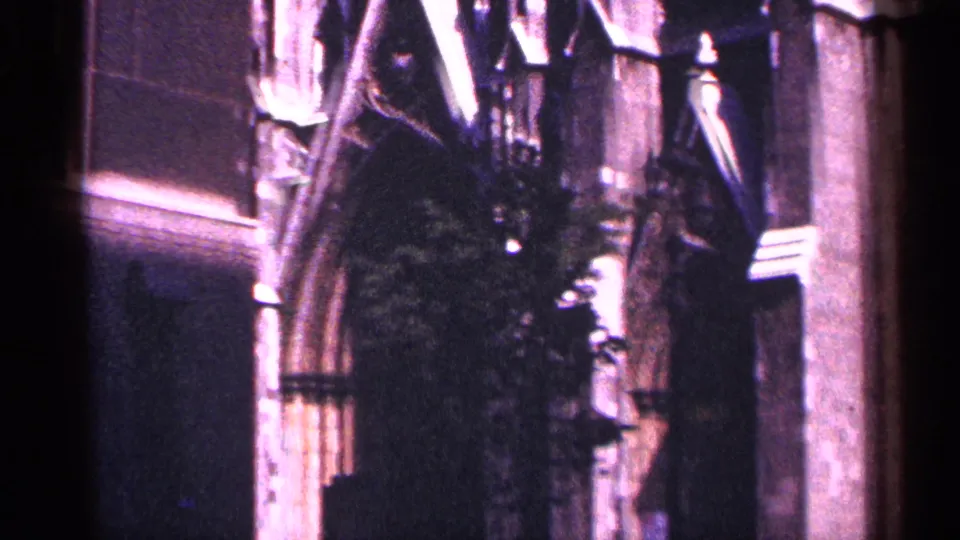 1964 New York City 8mm frame of Gothic-style cathedral architecture with a pointed arch, carved stone, and dark recesses.