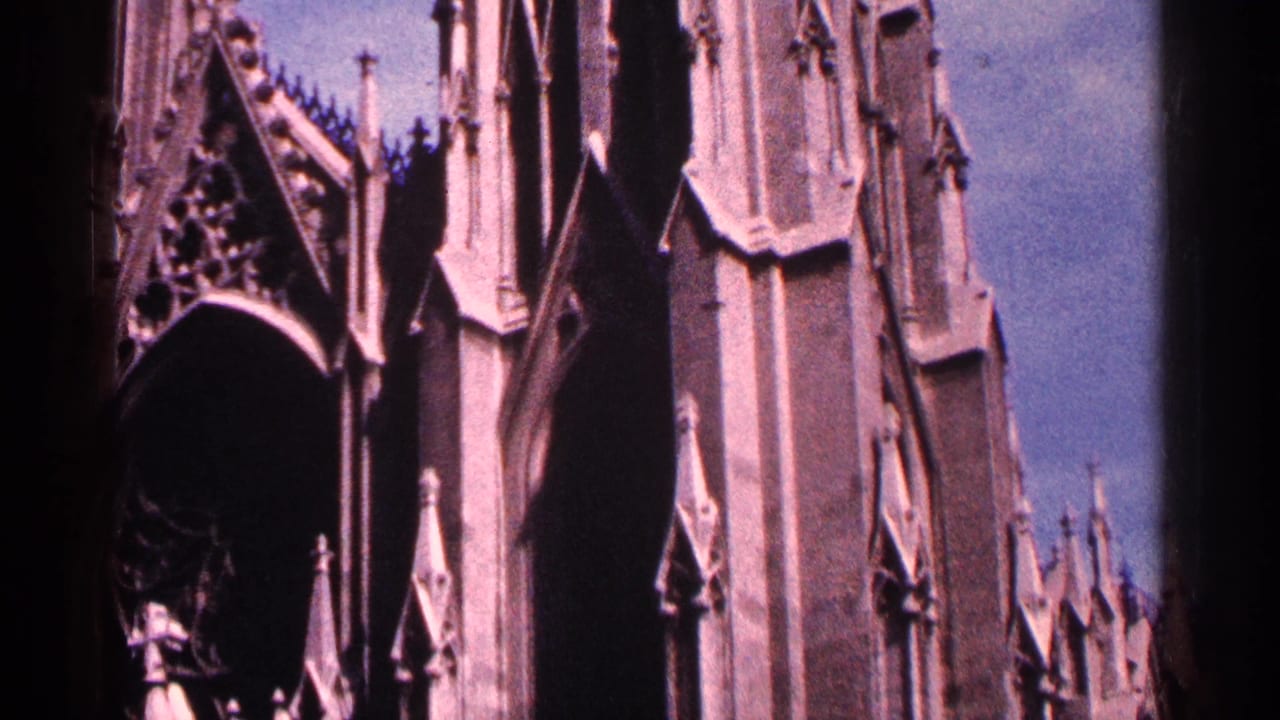 1964 New York City 8mm frame showing a Gothic church facade with pointed arches, carved stonework, and spire details.