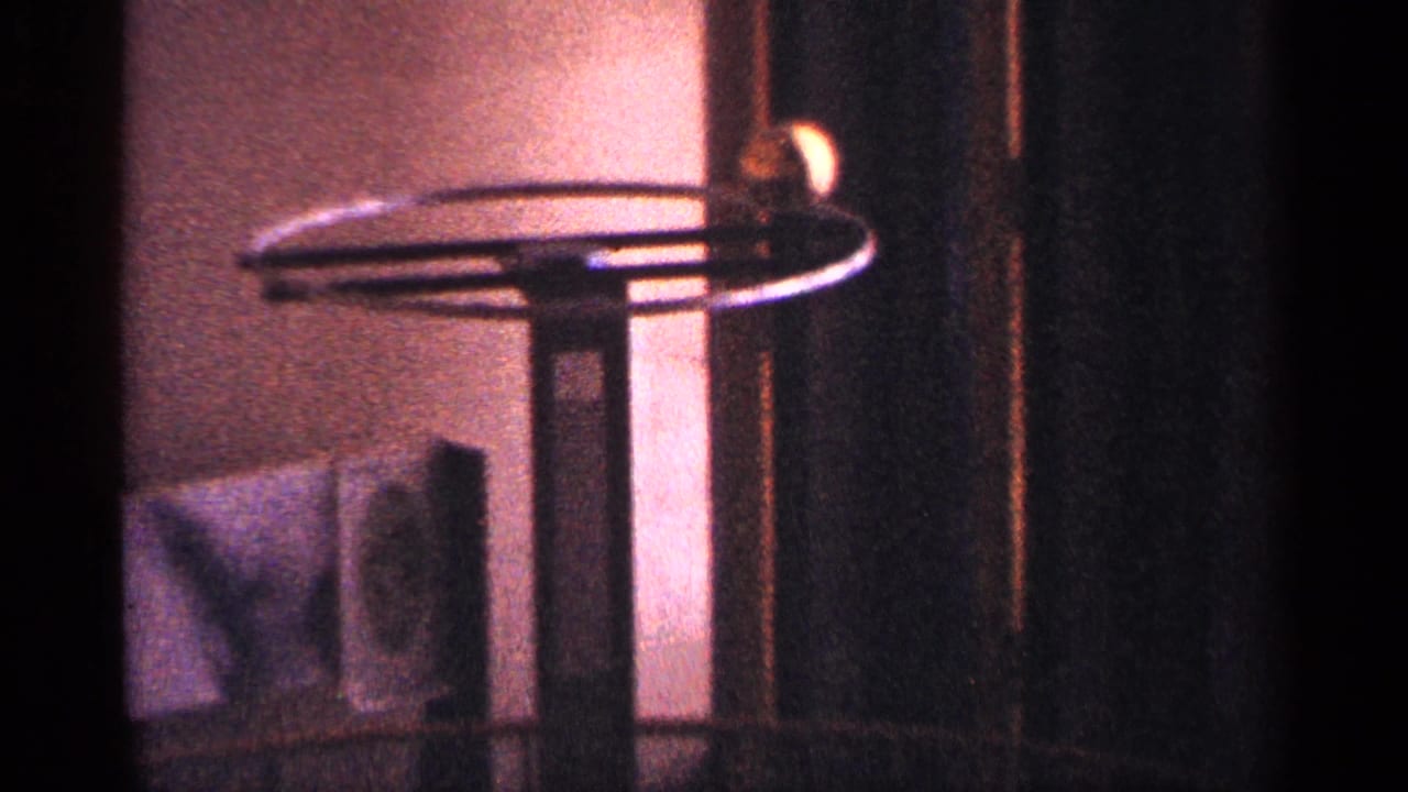 Warm-lit interior with a spinning tabletop object and dark vertical framing.