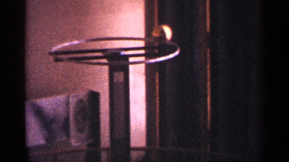 1964 New York City home-movie frame showing a warm-lit interior detail with a spinning mechanical or display object.