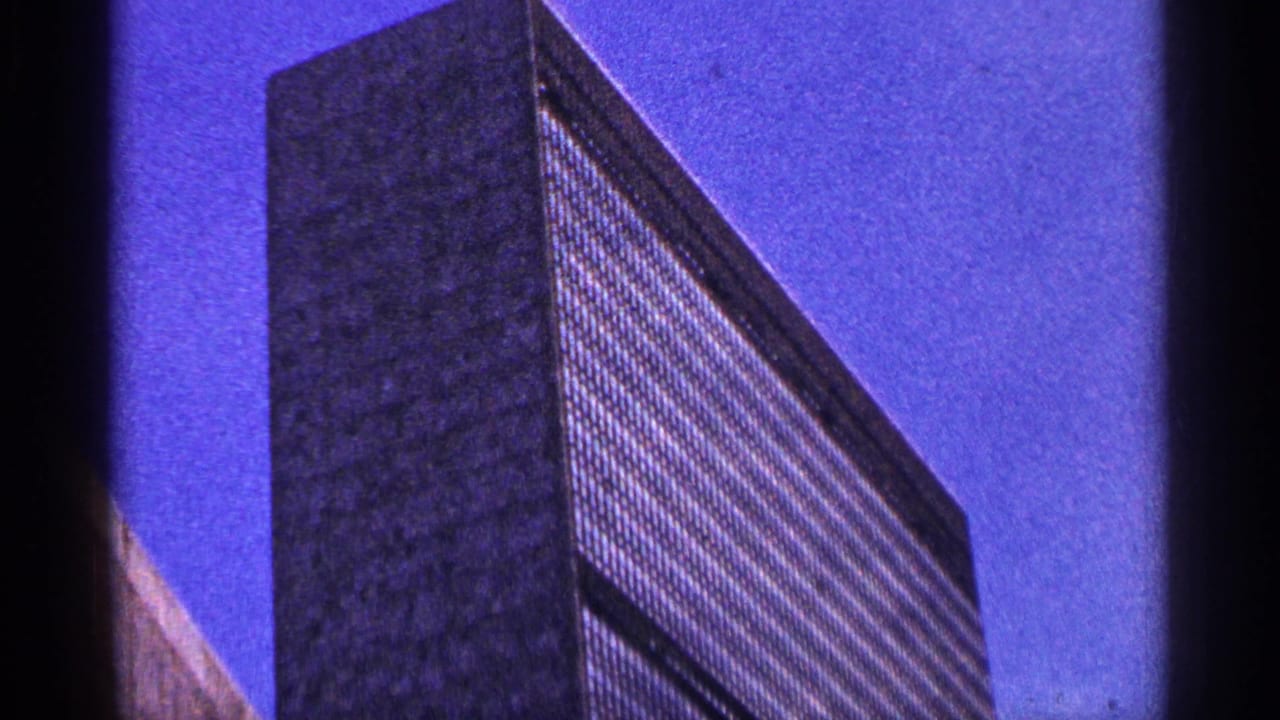 Low-angle view of a tall gridded building against a blue sky.