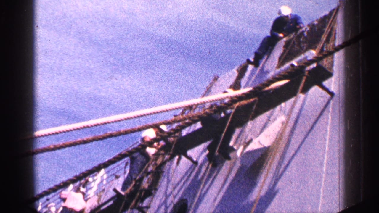 Workers on ropes and rigging along the side of a large ship under blue sky.