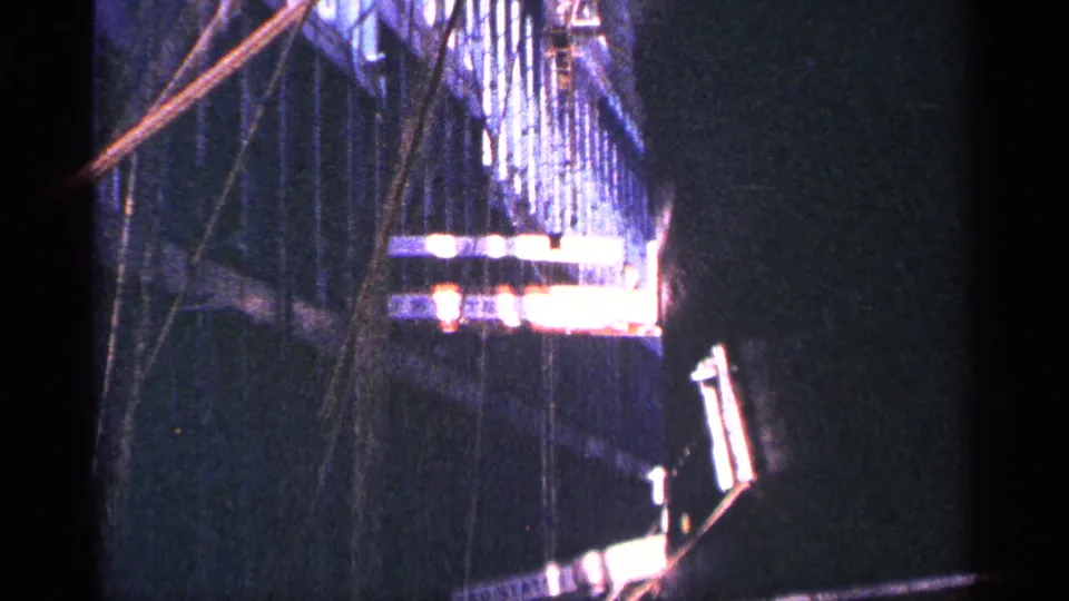 The final frame shows rigging and a bright platform or dock-side structure beside the dark mass of the ship.