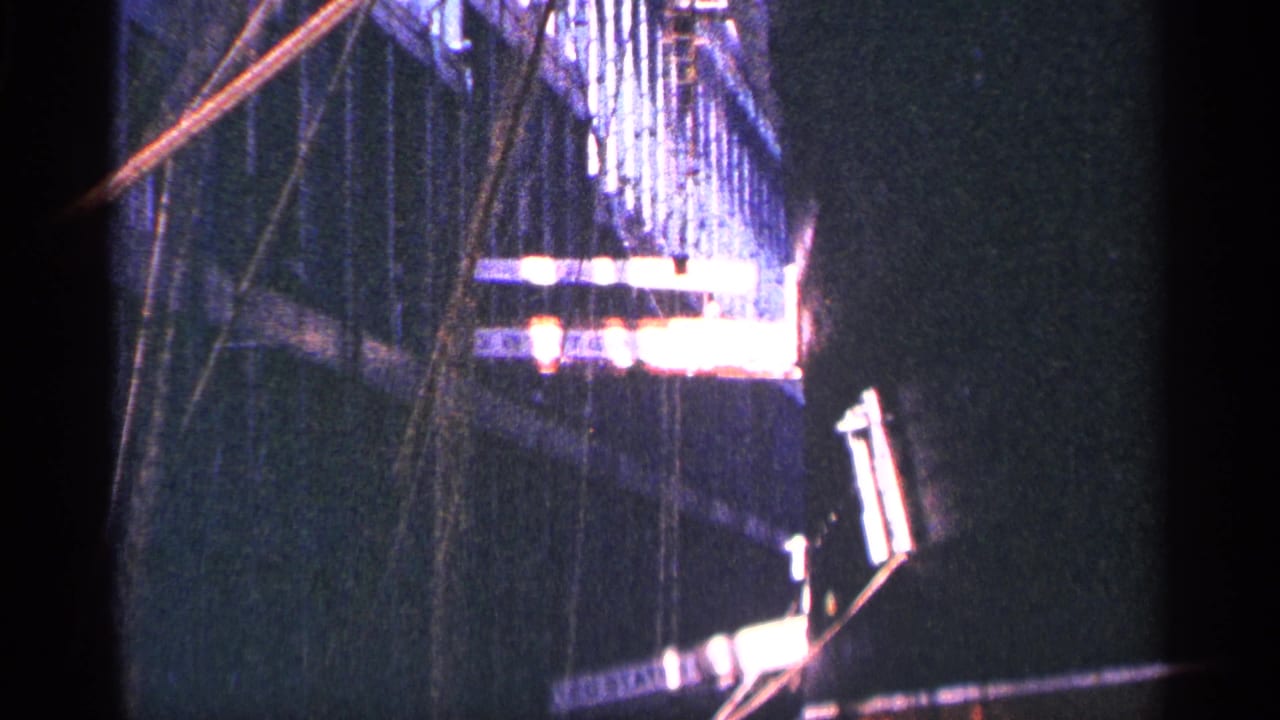 Dark, underexposed view with a partial structure and bright sign edge at frame right.