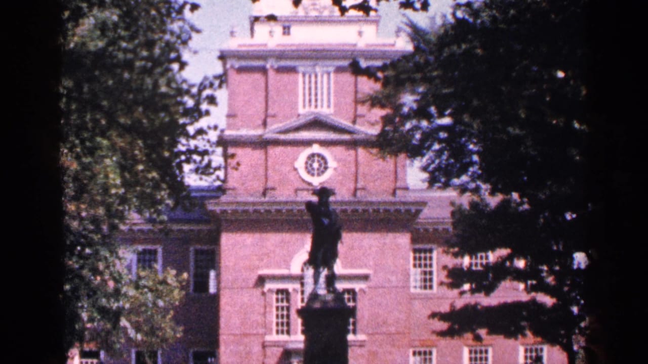 Brick historic building with statue in front and trees framing the view.