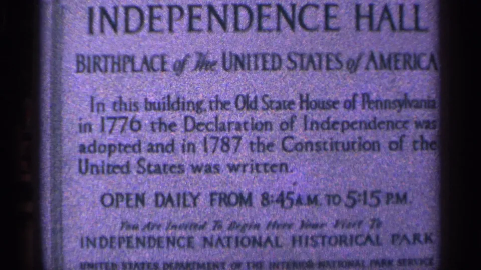 Close view of an Independence Hall sign at the Philadelphia historic site, photographed on grainy 8mm film.