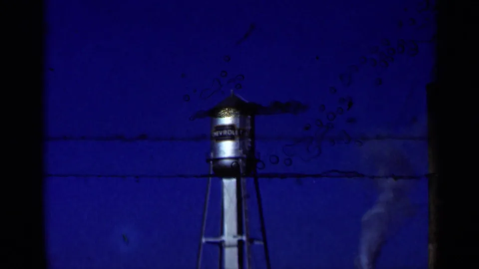 Water tower seen against a saturated blue sky in the Niagara Falls Canada 1964 home-movie footage, with heavy film edge intrusion.
