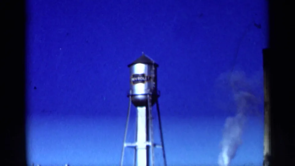 Tall water tower in the 1964 Niagara Falls Canada footage, framed against bright blue sky with a pale smoke plume nearby.