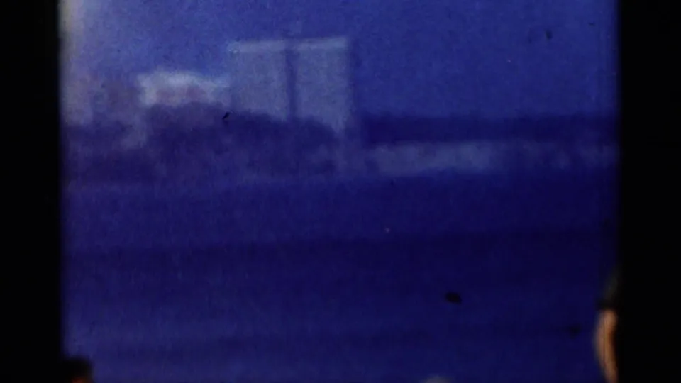 Blurred 8mm view of a distant structure or roofline, rendered in blue tones with visible grain and film borders.