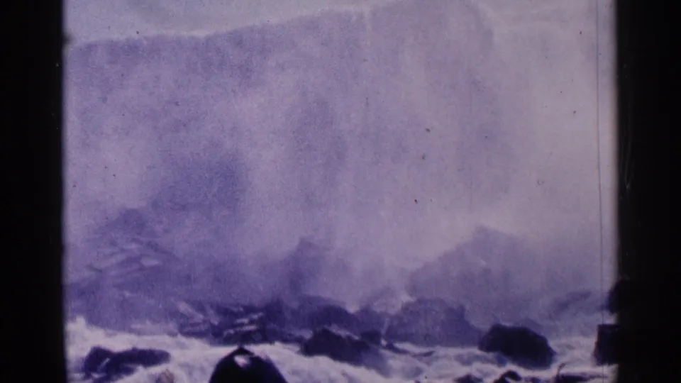 Niagara Falls, Canada, seen in soft purple 8mm color with spray rising above dark rocks.