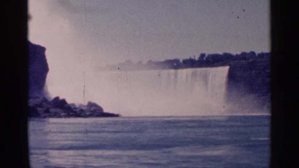 Canadian-side Niagara Falls view on 8mm film, showing the falls, mist, river, rocks, and soft faded color.