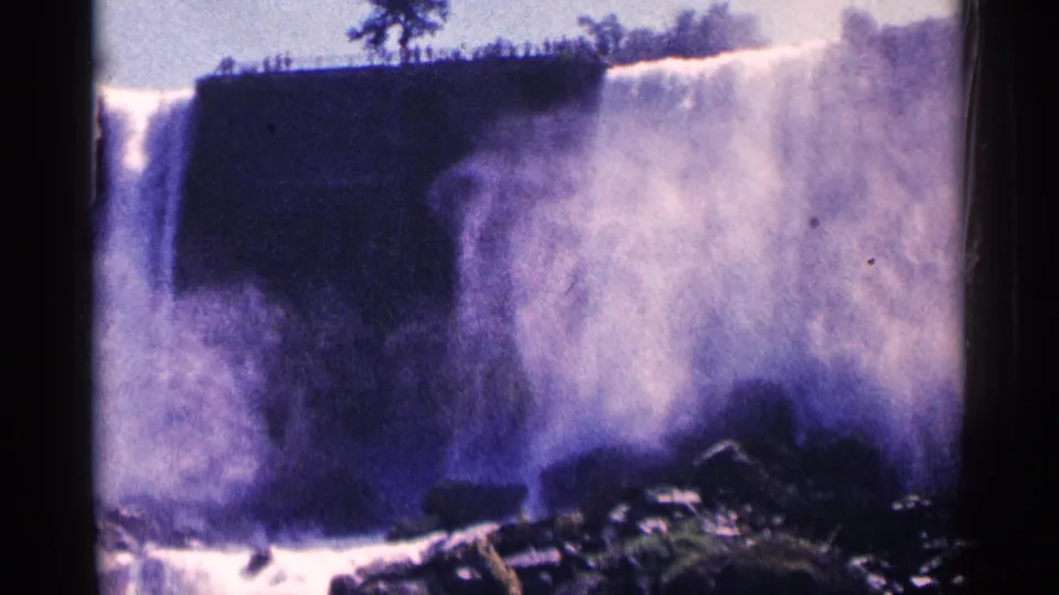 1964 8mm Niagara Falls frame with heavy spray obscuring the cliff and water churning around rocks below.