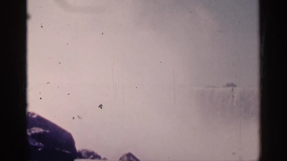 Misty 1964 Niagara Falls view with dark rocks at lower left and the waterfall partly obscured by spray.