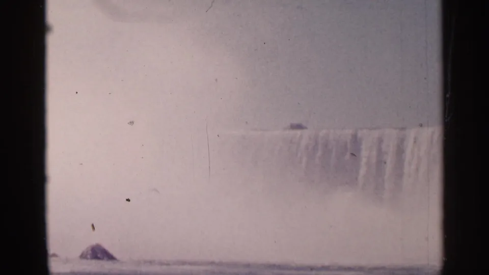 1964 8mm view of Niagara Falls, Canada, seen through haze and mist with visible gate edges and dust specks.