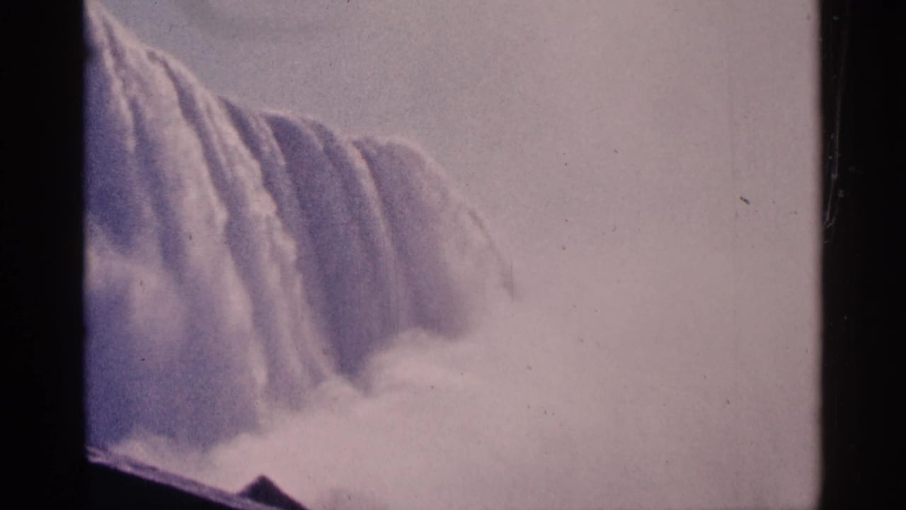 Wide waterfall spilling over a cliff with heavy mist below.