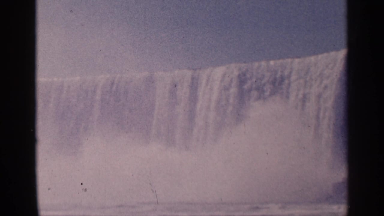 Broad curtain of waterfall with mist rising across the lower frame.