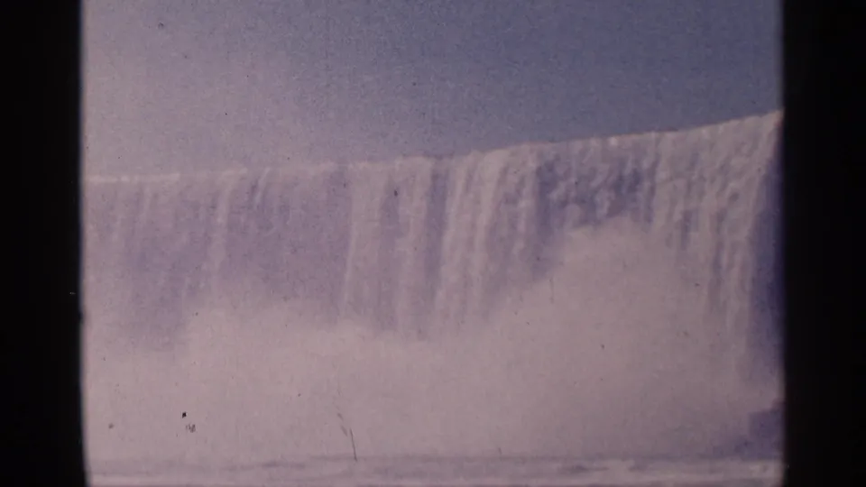 1964 8mm footage shows Niagara Falls as a long curtain of falling water, with spray obscuring the base.