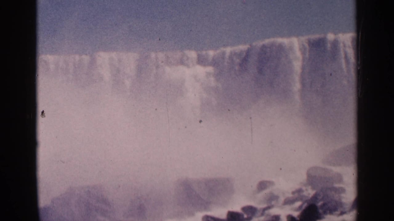 Wide curtain of falling water and mist seen through a film-frame border.