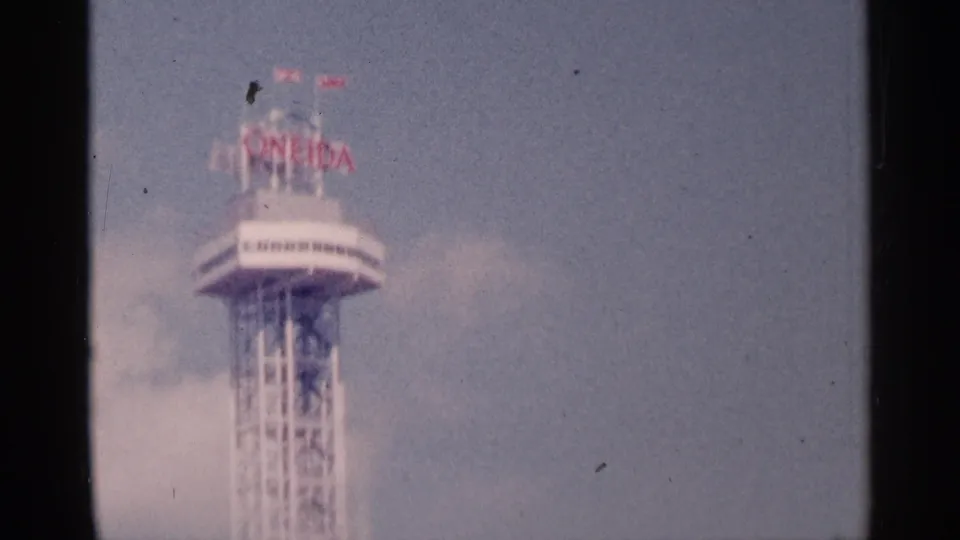 1964 Niagara Falls, Canada home-movie frame showing a tall tower under construction with red signage above the upper deck.