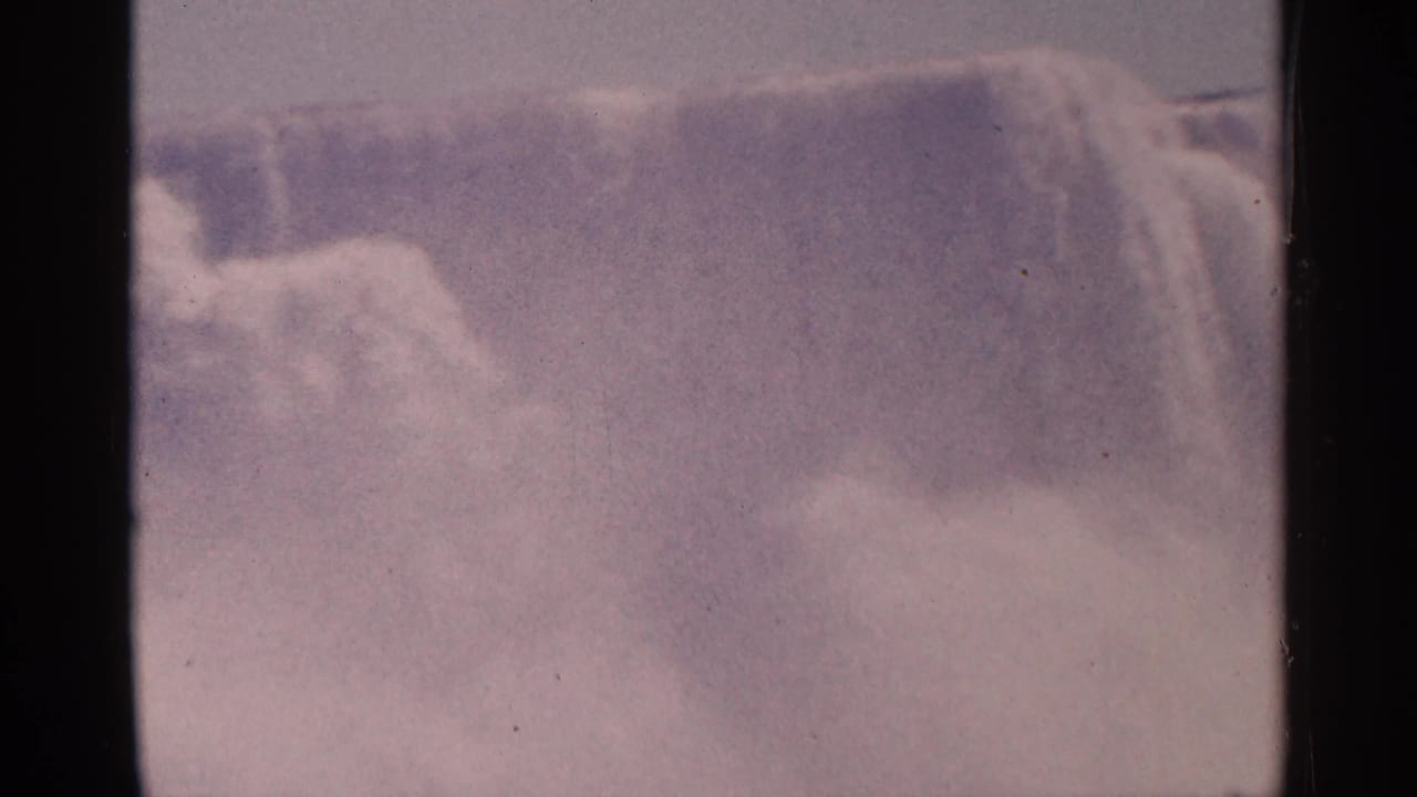 Water pours over a broad waterfall edge into thick mist.