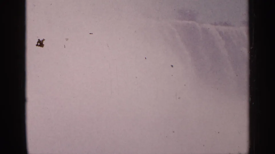 Faded 1964 8mm view of Niagara Falls with a softened waterfall edge, heavy mist, dust specks, and pink-purple color shift.