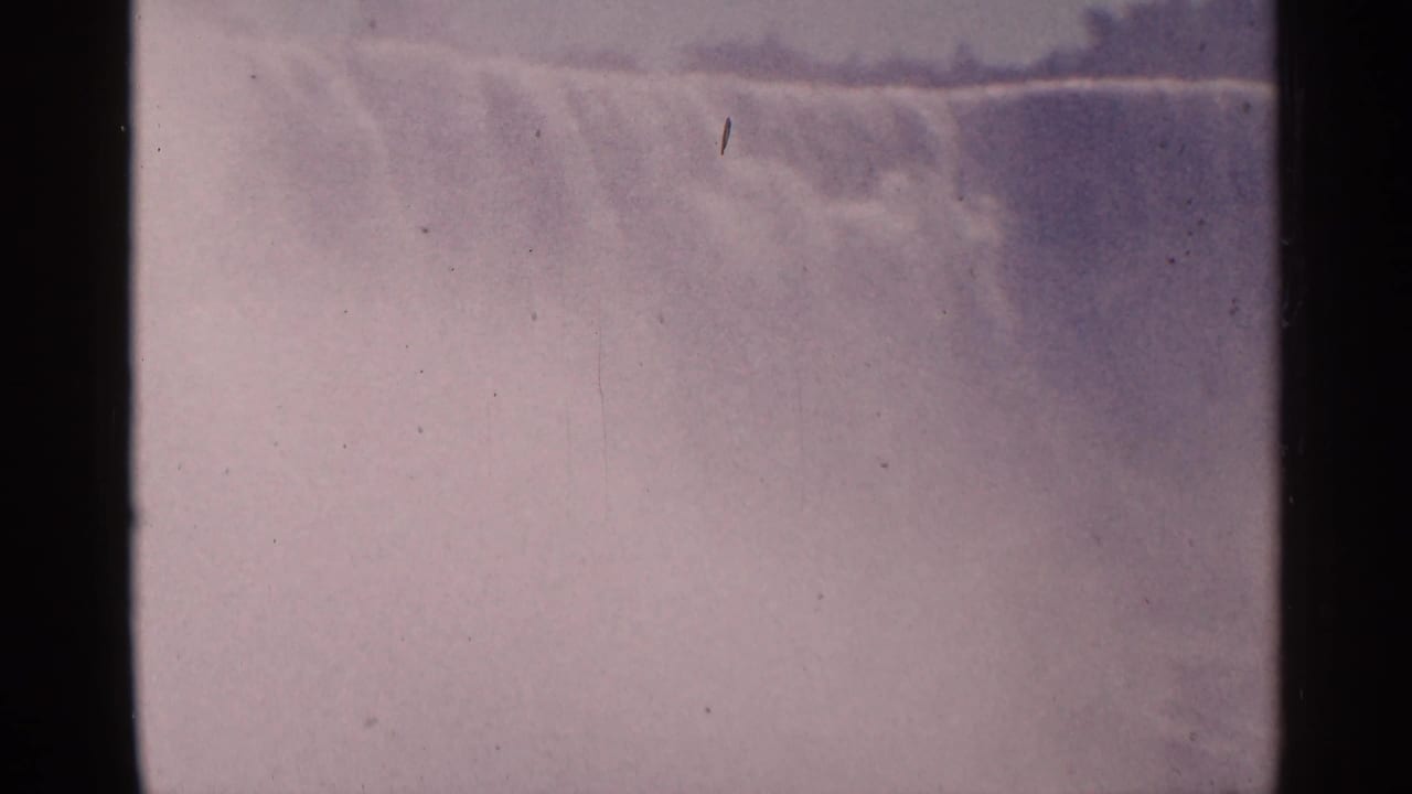 Hazy waterfall surface and mist framed by dark vertical film edges.