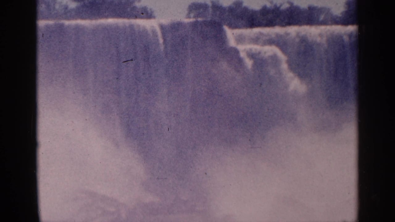 Waterfall crest and heavy mist with dark trees along the top edge.