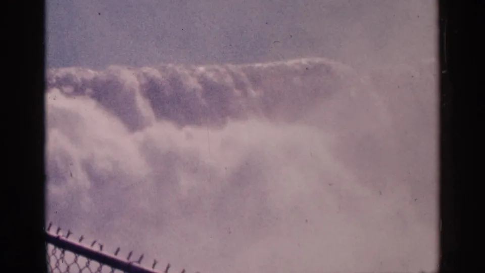 Mist-heavy view of Niagara Falls, Canada from a visitor viewing area, with chain-link fencing along the lower edge.