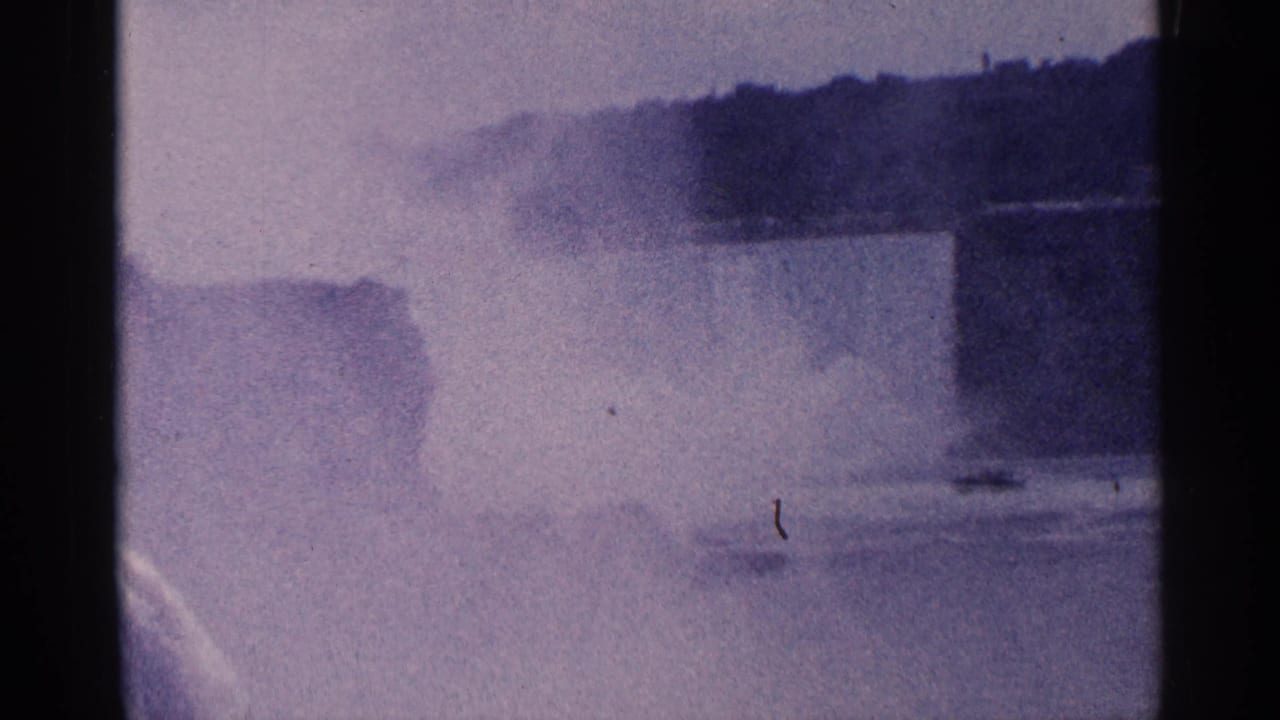 Mist over the falls and river, with a small dark speck near the lens.