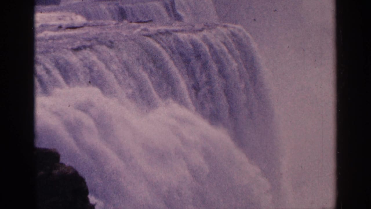 Close view of cascading waterfall water with mist and dark film edges.