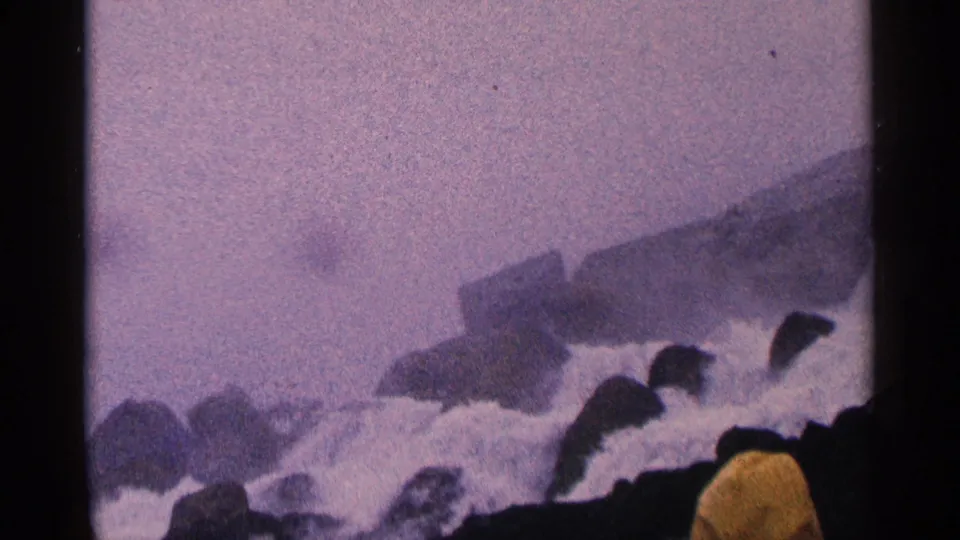 1964 8mm view near Niagara Falls, Canada, showing mist, rocks, turbulent water, and dark foreground silhouettes along the lower edge.