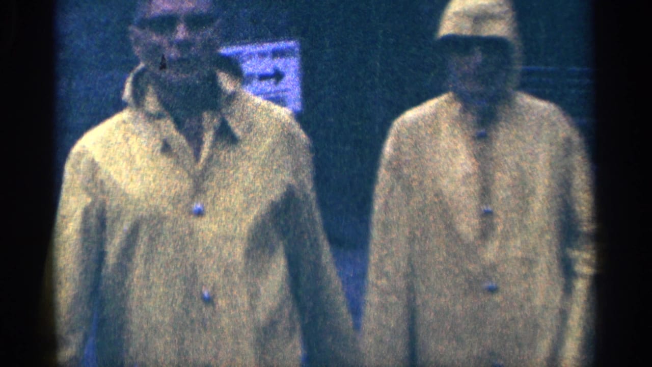 Two men in bright yellow raincoats walk near the camera in 1964 home-movie footage from Niagara Falls, Canada.