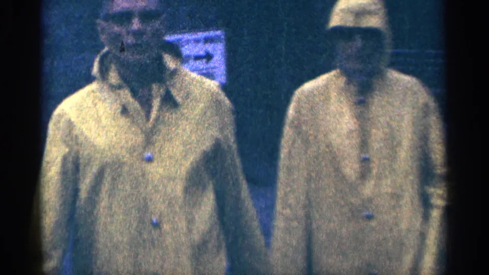 Two men in bright yellow raincoats walk near the camera in 1964 home-movie footage from Niagara Falls, Canada.