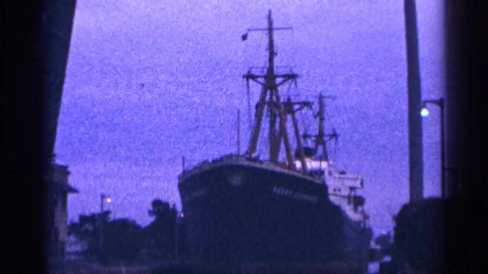 The final frame holds on the ship's bow and mast, partly framed by a dark vertical edge from the 8mm scan or camera position.